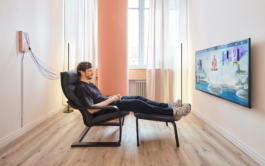 Ein Klient sitzt entspannt im Sessel während einer Neurofeedback-Sitzung, im Hintergrund ist der Monitor zur visuellen Rückmeldung sichtbar. 